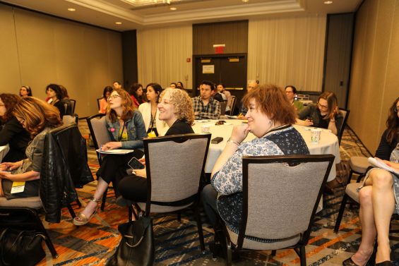 women listening to a workshop smiling