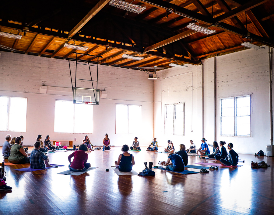 People sitting on the floor in a circle in a gym